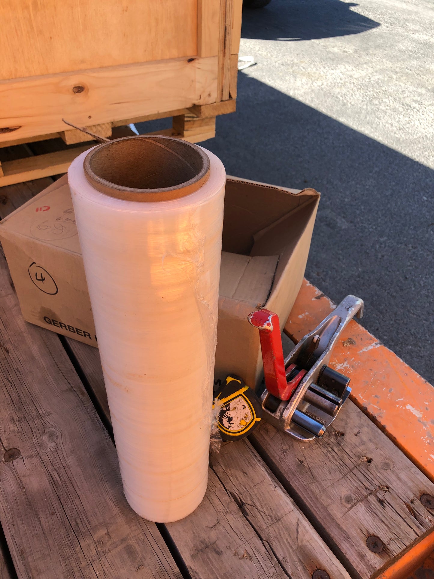 Roll of plastic wrap on a wooden pallet with packaging supplies.